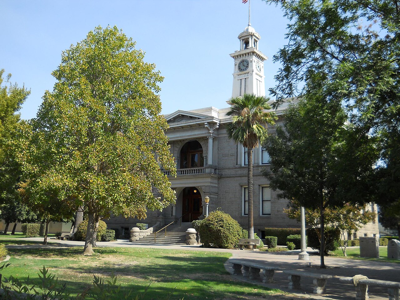 Madera County Courthouse and clock tower behind trees in Madera, California
